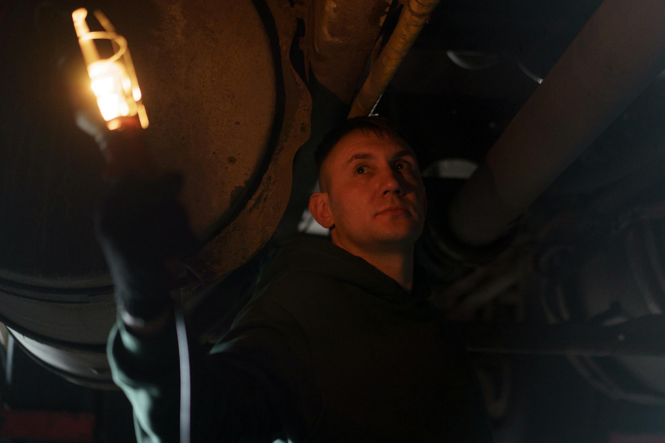 Mechanic inspecting with handheld lamp in dark workshop
