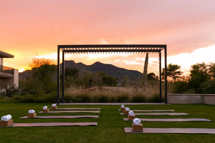 Resort lawn set for a sunrise yoga class, mats and towels laid out against the mountains